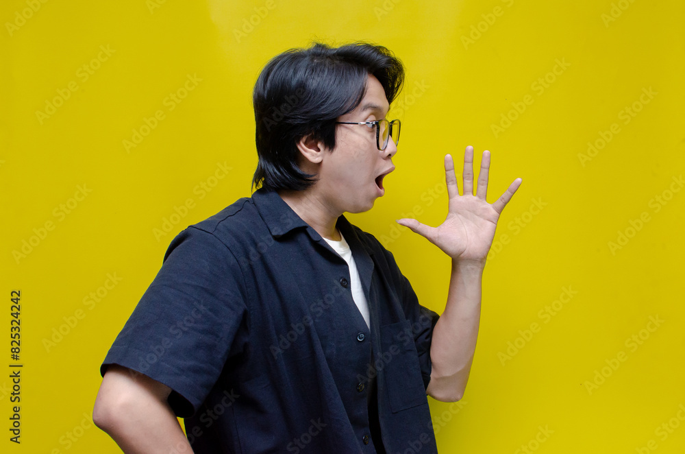 young asian man hand on mouth telling secret and whispering gossip. asian man opening mouth shouting happily young asian man hand on mouth telling secret and whispering gossip. asian man opening mouth shouting happily