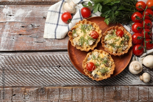 Tasty tartlets with cheese, tomatoes, mushrooms and dill on wooden rustic table, flat lay. Space for text