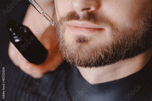 Spa care for men hair, barber use dropper with oil for beard of man in barbarshop photo