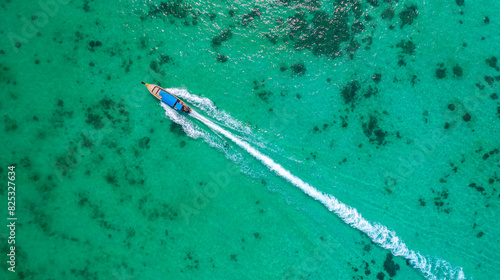 Aerial view capturing tranquil beauty of clear turquoise sea with solitary thai long tail boat creating frothy trail on water surface. Travel banner photo of Thailand