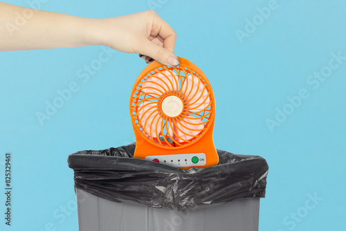 throw the portable table fan into the trash, outstretched hand with fan in front of the trash can