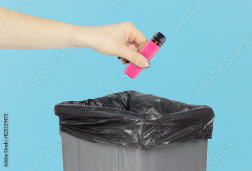 throw the electronic cigarette into the trash, outstretched hand with electronic cigarette in front of the trash can, concept of harm from electronic cigarettes