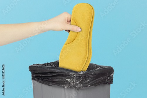 throw orthopedic shoe insoles in the trash, outstretched hand with felt insoles  in front of trash can