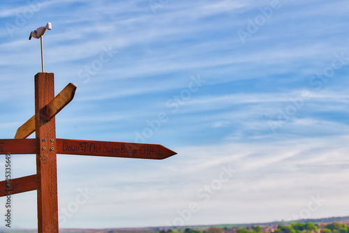 Wooden signpost with directional arrows under blue sky in Whitby, North Yorkshire