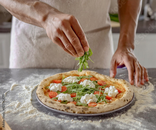Front view of a chef sprinkling herbs onto a baked pizza.