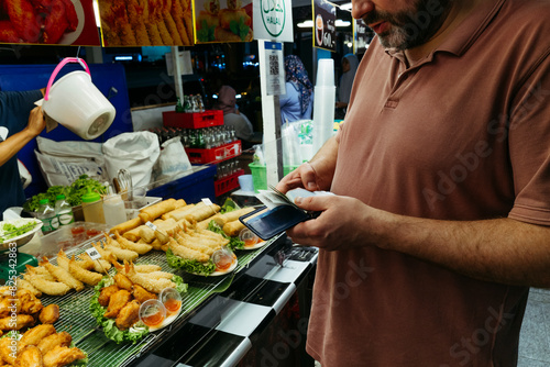 Man Paying at Street Food Stall at Night photo