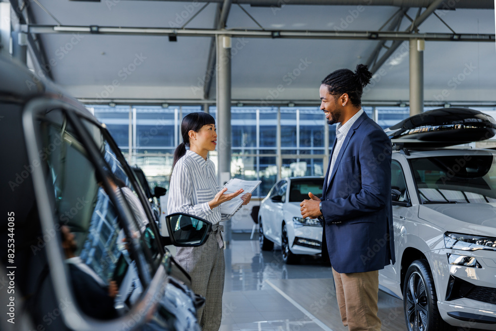 Two car dealership employees having a conversation in the showroom Two car dealership employees having a conversation in the showroom