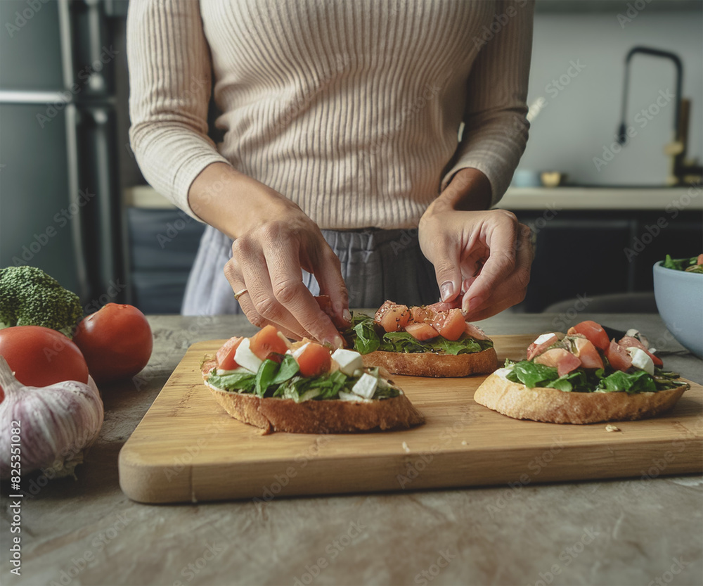A woman in her kitchen preparing salmon, cheese, avocado, and spinach toast.