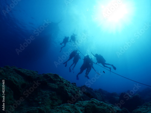 scuba divers holding on boat rope underwater  photo