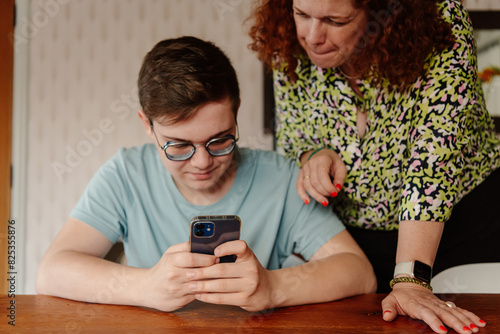 Teenager helping mom with phone  photo