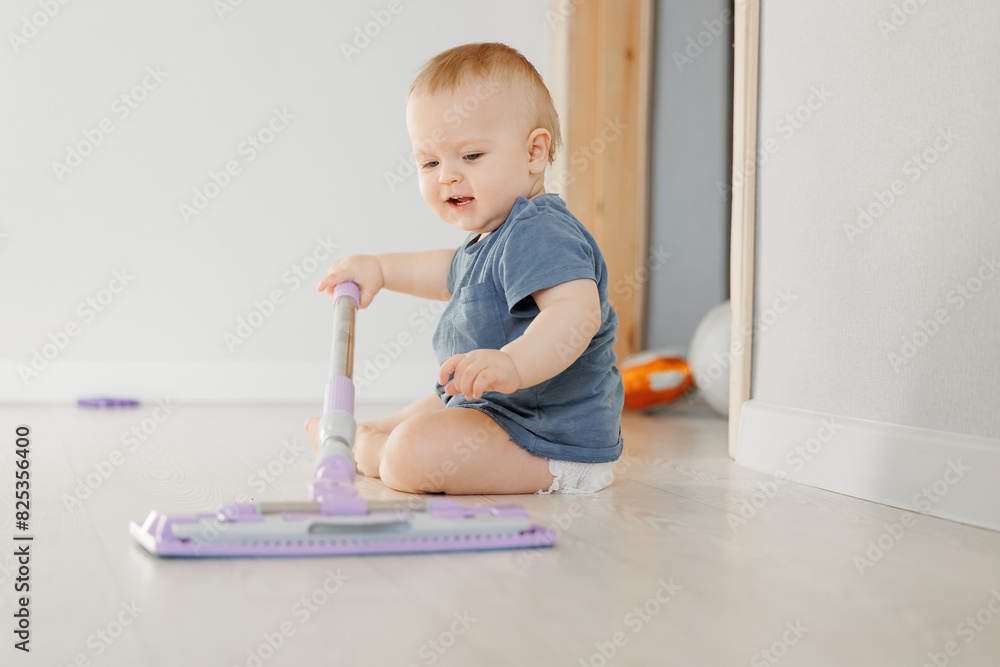 Happy young boy sitting on floor and holding mop for washing. Concept house helper from diapers Happy young boy sitting on floor and holding mop for washing. Concept house helper from diapers