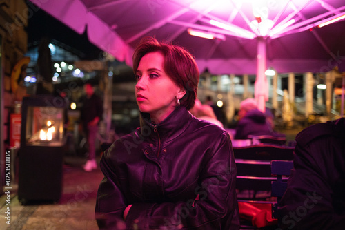 Bored woman at outdoor café with pink lighting