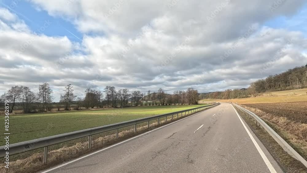 Paved road passing through fields and hills in the countryside on a sunny day Paved road passing through fields and hills in the countryside on a sunny day