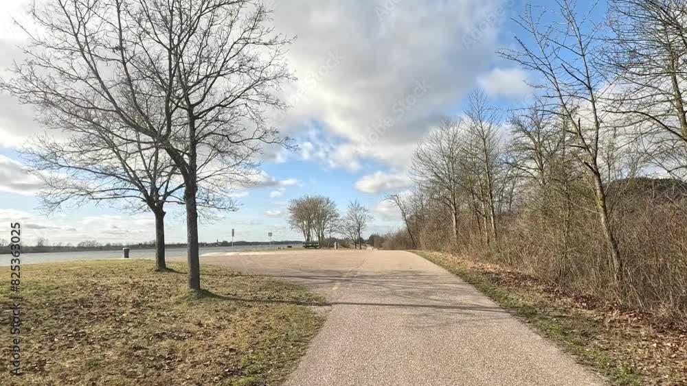 Narrow paved road with leafless trees leading to the shore of the Danube River Narrow paved road with leafless trees leading to the shore of the Danube River