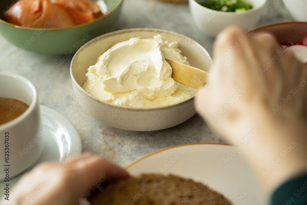Woman spreading ricotta cheese on toast Woman spreading ricotta cheese on toast