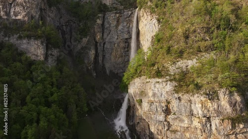 Aerial view of Seerenbach Falls, cascading down a rugged cliff surrounded by lush greenery, located near Betlis in the Amden municipality, Switzerland. photo