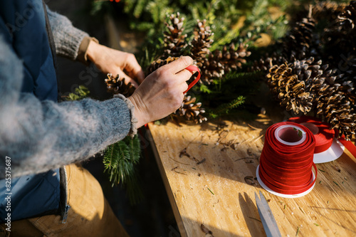 female farmer working in a greenhouse with pinecones for holiday decor photo