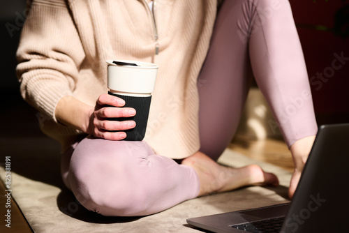Faceless Yogi with Coffee Cup Using Laptop on Floor photo