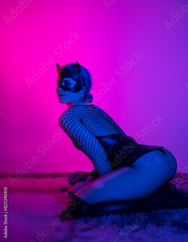 sexy girl in costume and mask bdsm games in neon light with empty background