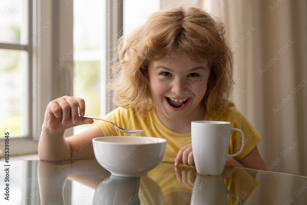 Excited funny happy kid eating low fat soy milk in bowl and serial. Food for good health. A cute little boy eating breakfast at home. Child with spoon and bowl having dinner at dining table. Excited funny happy kid eating low fat soy milk in bowl and serial. Food for good health. A cute little boy eating breakfast at home. Child with spoon and bowl having dinner at dining table.