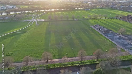 A top view shot over the ornamental pond of Nottingham War Memorial Gardens and Meadows Recreation Ground: vivid green fields are illuminated by sunset rays photo