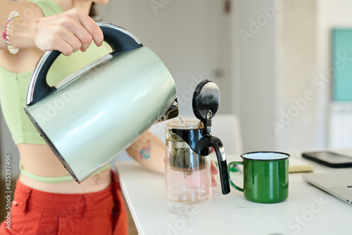 Pouring Hot Water to infuse tea in the teapot photo