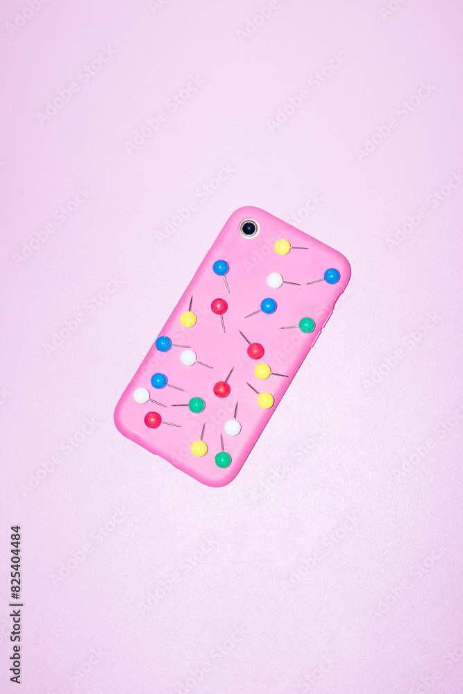 Pink smartphone and colorful paper pins with hard direct flashlight Pink smartphone and colorful paper pins with hard direct flashlight