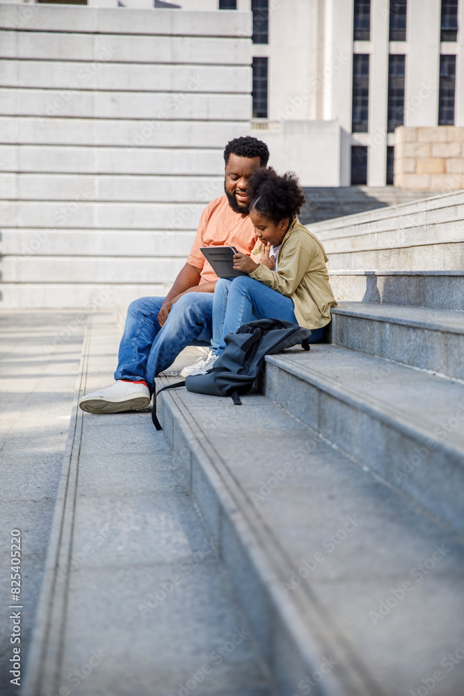 Father talking with daughter using digital tablet on steps Father talking with daughter using digital tablet on steps