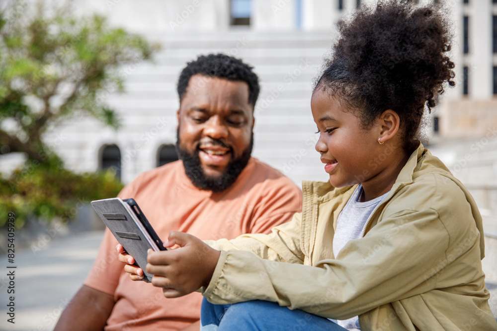Happy father looking at daughter using tablet PC Happy father looking at daughter using tablet PC