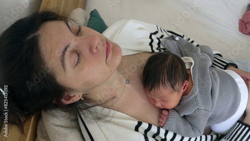 Tired Mother and newborn baby sleeping during infant's first week of life, fatigued parent regaining energy in the first days of life of a human being, nap time