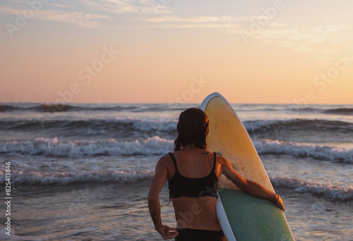 Woman with surfboard at sunset  photo