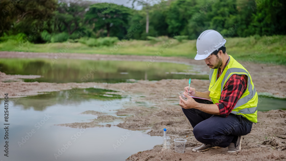 Environmental engineer Sit down next to a well and take note while holding the glass tube in his left hand to analysing check the quality and contaminants in the water source.