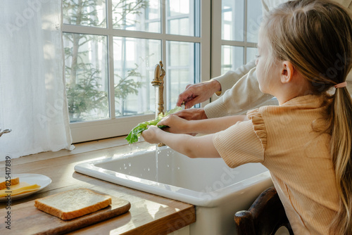 Child washing lettuce at kitchen sink photo