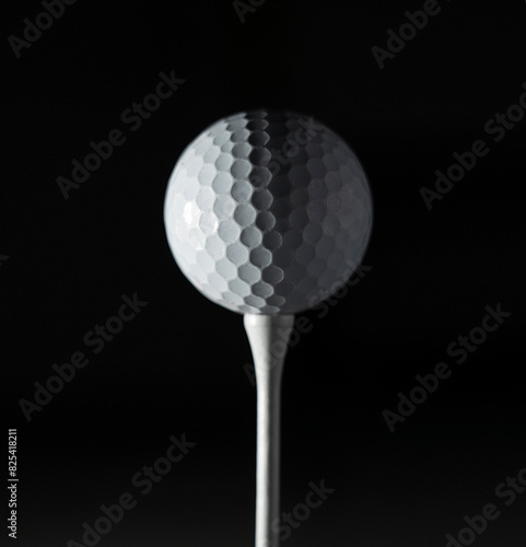 close up of a golf ball on a tee against a black background