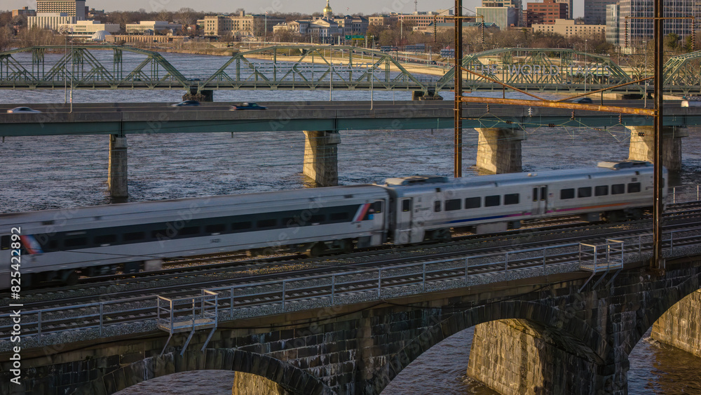 a silver train traveling over a bridge with other trains passing by