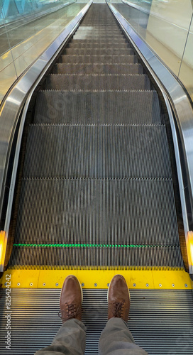 Leather Shoes stepping on escalator going down stairs  photo