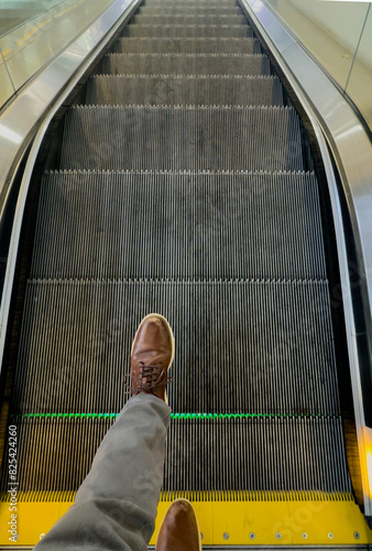 Shoes stepping on to escalator going down stairs  photo