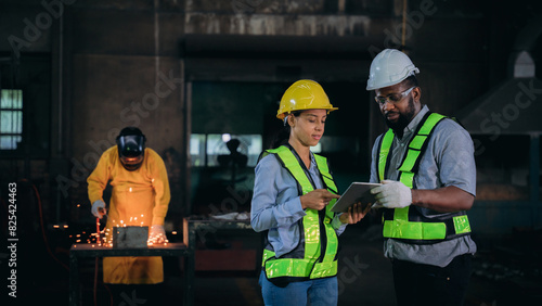 A group of workers are standing in a factory, one of them holding a tablet