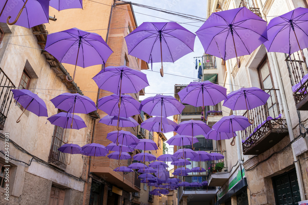 Naklejka premium Multitude of purple umbrellas hanging in the middle of the street decorating.