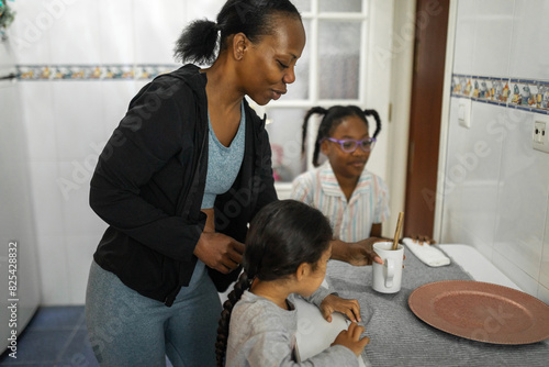 black mother with daughters having breakfast in kitchen at home photo