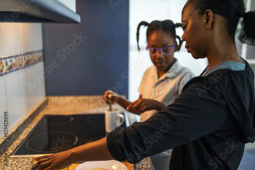 black mom making breakfast with her daughter at home photo