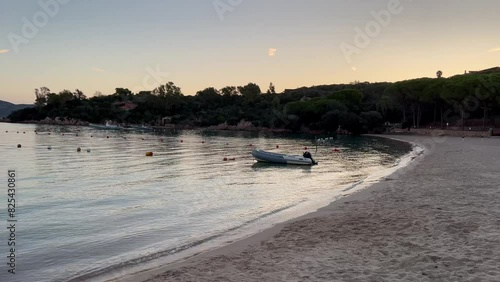 A motorboat docked near the beachline of Cala Suaraccia with calm waves in the morning photo