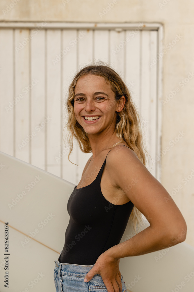 young woman holding surf board smiling at camera young woman holding surf board smiling at camera