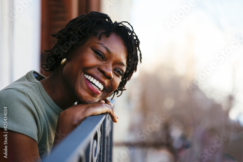 Cheerful woman smiling on small balcony photo