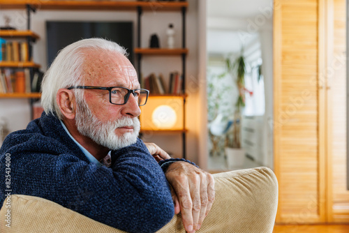 Thoughtful elderly man leaning on sofa photo