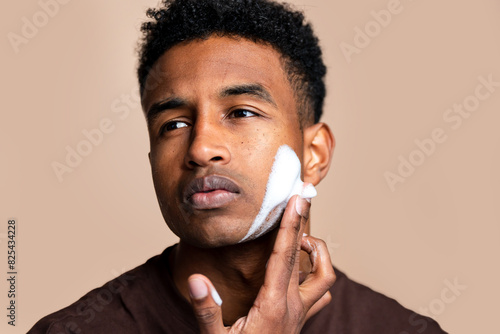 Young man is gently applying aftershave to his face  photo