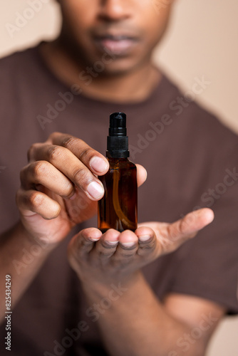 Man presenting cosmetic spray bottle photo