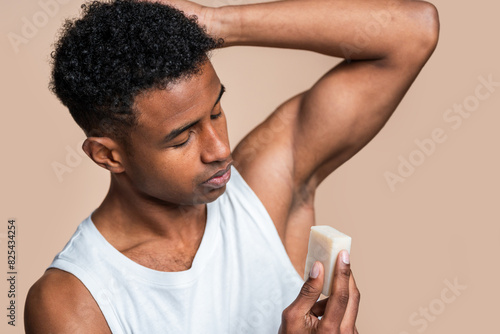 African american man in a white tank top applying stick deodorant