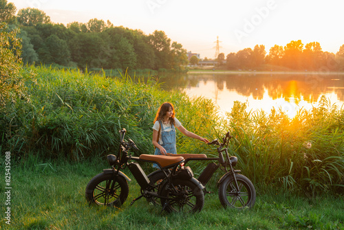 Woman standing near the motorcycle by the lake in summer  photo