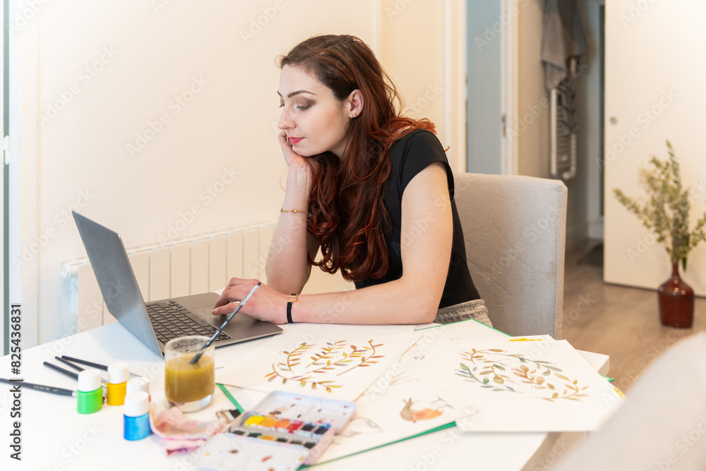 Woman Using A Laptop And Painting An Illustration At Home. Woman Using A Laptop And Painting An Illustration At Home.